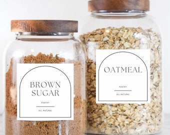 May include: Two glass jars with wooden lids and labels. The jar on the left contains brown sugar and has a label that reads "BROWN SUGAR, PANTRY, ALL NATURAL". The jar on the right contains oatmeal and has a label that reads "OATMEAL, PANTRY, ALL NATURAL".