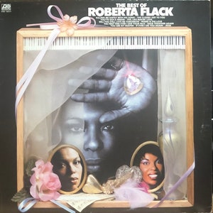 May include: Album cover for "The Best of Roberta Flack" featuring a black and white portrait of the singer. The cover includes a wooden frame with a piano keyboard design, decorative elements, and song titles.