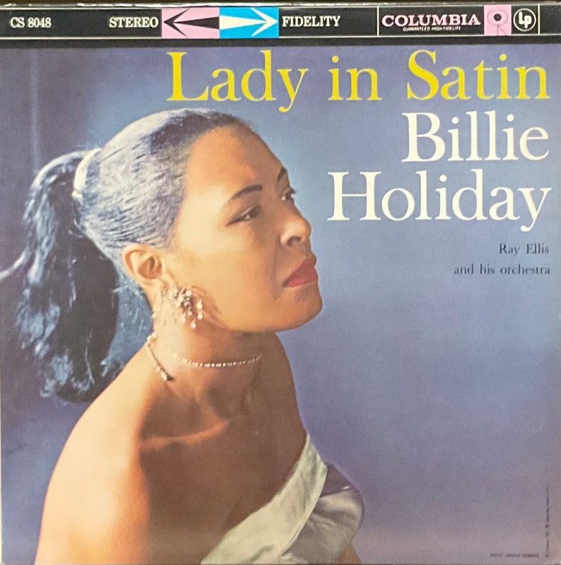 Op de afbeelding: Een vintage vinyl platenhoes met een portret van Billie Holiday, een beroemde jazzzangeres, met de titel "Lady in Satin" en de naam van de orkestleider, Ray Ellis, in witte tekst op een blauwe achtergrond.