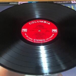 Op de afbeelding: Een zwarte vinylplaat met een rood label waarop "Columbia" en "Lady in Satin" staat met de artiest "Julie London" erop gedrukt. De plaat is in stereo-formaat en heeft een 360-geluid.