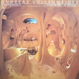 May include: A record album cover featuring a surreal, cave-like interior with a light brown color scheme. The album title "CAVERNA MAGICA" is printed in black text at the top, along with the artist's name "ANDREAS VOLLENWEIDER" and the subtitle "(...UNDER THE TREE - IN THE CAVE...)".