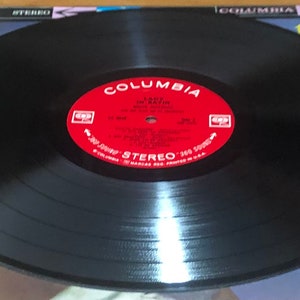 Op de afbeelding: Een zwarte vinylplaat met een rood label waarop "Columbia" en "Lady In Satin" van "Billie Holiday" staat met het orkest onder leiding van "Gerry Mulligan".