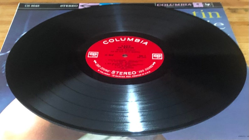 Op de afbeelding: Een zwarte vinylplaat met een rood label waarop "Columbia" en "Lady In Satin" van "Billie Holiday" staat met het orkest onder leiding van "Gerry Mulligan".