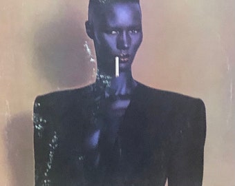 Op de afbeelding: Een zwart-wit albumhoes met een vrouw met kort zwart haar en een zwart colbert. De albumtitel "Grace Jones Nightclubbing" staat bovenaan de hoes gedrukt.