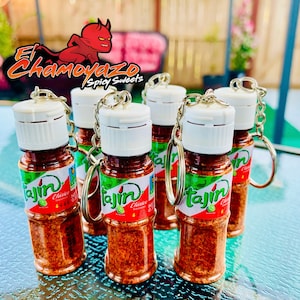 May include: Five small clear glass bottles with white lids and silver keychains. Each bottle contains red and orange Tajin seasoning and has a green and white label with the text "Tajin Clasico Seasoning" and a lime image.