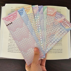 May include: A set of colourful reading trackers with different time increments, including 15 minutes, 30 minutes, 1 hour, and pages read. The trackers are made of cardstock and have a rainbow gradient design.
