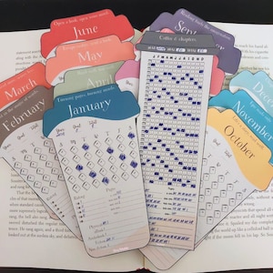 May include: A set of 12 colourful bookmarks with a coffee cup design. Each bookmark features a different month of the year and a reading goal tracker. The bookmarks are decorated with motivational quotes about reading.