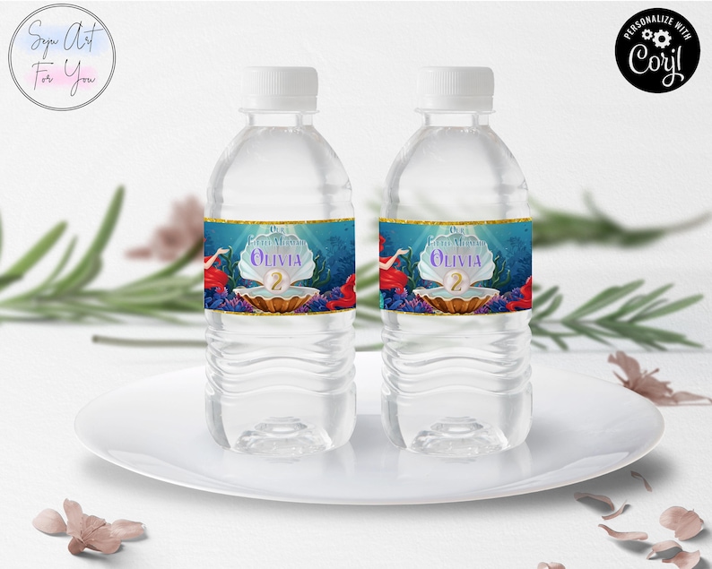 May include: Two clear water bottles with white caps, each featuring a custom label. The labels showcase a mermaid theme with a pearl, the name "Olivia", and the number "2". The design includes red, blue, and gold accents, set against a blue underwater backdrop.