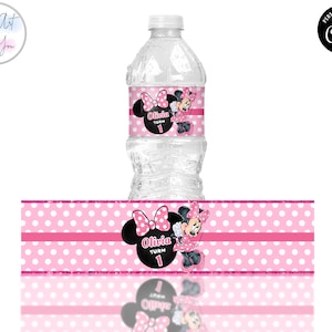 K&ouml;nnte beinhalten: Eine transparente Plastikwasserflasche mit einem rosa-wei&szlig; gepunkteten Etikett mit einem Minnie Mouse-Design. Das Etikett enth&auml;lt den Namen "Olivia" und die Zahl "1". Das Design wird auf einem separaten Etikett wiederholt.