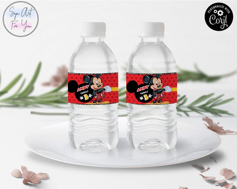 Puede incluir: Dos botellas de agua de pl&aacute;stico transparente con tapas blancas. Cada botella tiene una etiqueta roja con Mickey Mouse, el texto "ANDY TURNS 1" y una franja amarilla. Las botellas est&aacute;n sobre un plato blanco.