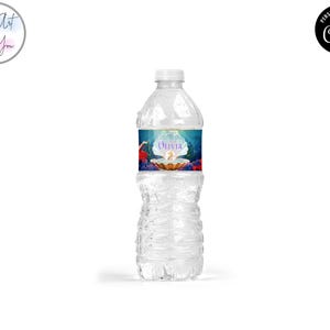 May include: A clear plastic water bottle with a white cap. The label features a mermaid theme with the name "Olivia" and the number "2". The label has a blue, teal, and gold color scheme.