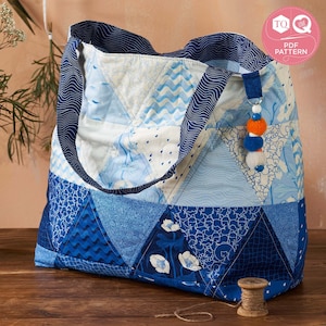 May include: A blue and white patchwork tote bag with a blue and white patterned fabric. The bag has a blue handle and a blue and white tassel. The bag is sitting on a wooden surface.  TQ Love PDF Pattern.