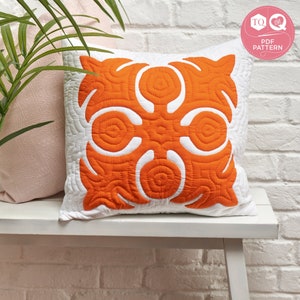 May include: Orange and white quilted pillow with a geometric pattern. The pillow is sitting on a white bench in front of a white brick wall. The text "TO LOVE PDF PATTERN" is on a pink circle in the upper right corner of the image.
