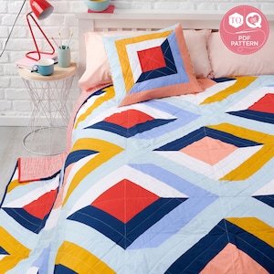 以下が含まれることがあります： 赤、黄色、青、ピンクの色合いで幾何学模様が施されたカラフルなキルト。キルトはさまざまな生地で作られており、モダンなデザインです。キルトは、それに合わせた枕のあるベッドの上に置かれています。