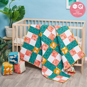 Puede incluir: Una colcha de retazos de color turquesa, blanco, rosa y amarillo con un patrón floral. La colcha está doblada y drapeada sobre una cuna de madera.