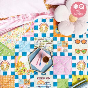 May include: A colorful patchwork quilt with a blue and white checkered pattern. The quilt features various designs, including flowers, rainbows, and the phrases "Take it Easy" and "Keep on Truckin".
