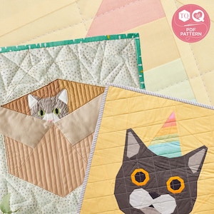 Puede incluir: Dos bloques de acolchado con un diseño de gato. El primer bloque es un fondo verde y blanco con un gato marrón asomándose de una caja. El segundo bloque es un fondo amarillo con un gato gris que lleva un gorro de fiesta arcoíris.