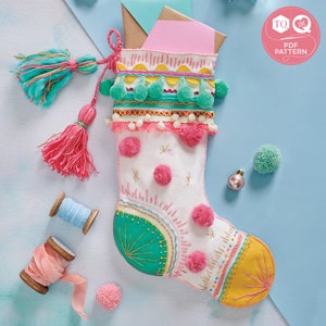 May include: A white Christmas stocking with a colorful embroidered design. The stocking has a pink pom-pom trim, green pom-poms, and yellow and turquoise accents. The stocking is decorated with stars and a "TO LOVE" tag.
