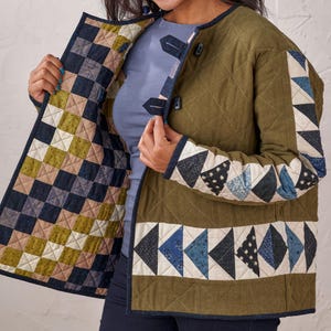 Puede incluir: Chaqueta acolchada verde oliva con dise&ntilde;o patchwork. La chaqueta presenta un patr&oacute;n de diamantes, con tri&aacute;ngulos y cuadrados de patchwork en tonos azules, blancos y beige. Tiene cierre de botones y ribete azul oscuro en contraste.