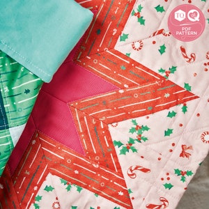 May include: A pink, red and green patchwork quilt with a star design. The quilt is made of different fabrics with various patterns, including holly leaves, candy canes and stripes.