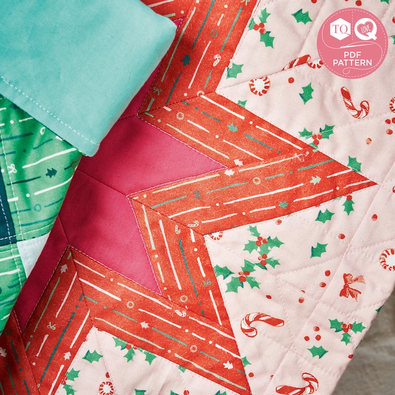 May include: A pink, red and green patchwork quilt with a star design. The quilt is made of different fabrics with various patterns, including holly leaves, candy canes and stripes.