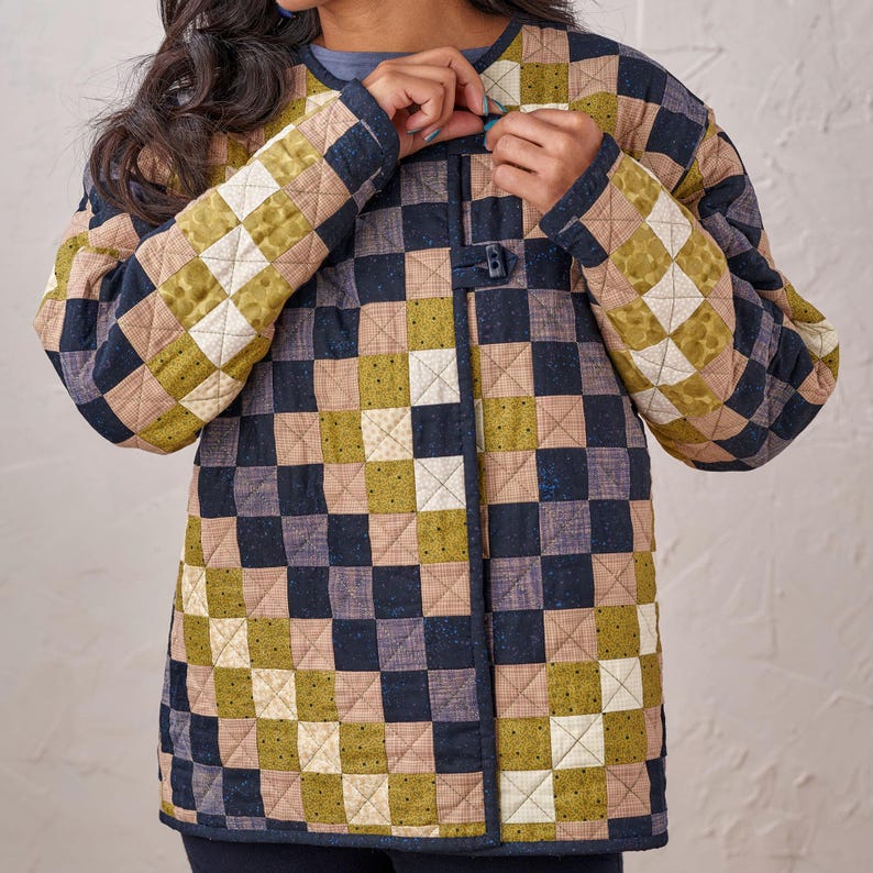 Puede incluir: Una chaqueta acolchada con un patr&oacute;n de tablero de ajedrez en tonos azul marino, verde oliva, beige y crema. La chaqueta tiene mangas largas y cierre de bot&oacute;n. La tela parece ser de algod&oacute;n o similar.