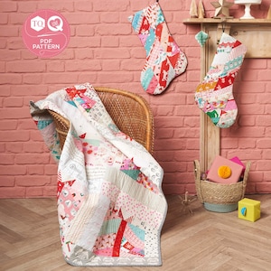 May include: A patchwork quilt with a white background and red, pink, and blue accents. The quilt is draped over a wicker chair. Two patchwork stockings hang on a brick wall behind the chair. The stockings are also red, pink, and blue. The text "TQ Love PDF Pattern" is in a pink circle on the wall.