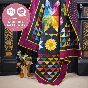 Può includere: Una trapunta colorata con un motivo a stella e girasole. La trapunta presenta uno sfondo nero con forme geometriche in vari colori, tra cui giallo, blu e rosso. Ha un bordo viola con finiture gialle. L'immagine include il testo "TQ Love Quilting Patterns."