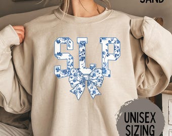 May include: A beige sweatshirt with a blue floral print design that spells out "SLP" with a blue floral bow underneath. The sweatshirt is unisex sizing.