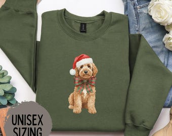 May include: Military green sweatshirt with a graphic of a dog wearing a Santa hat and a plaid bow. The text "MILITARY GREEN" is above the graphic, and "UNISEX SIZING" is below. The sweatshirt is a crew neck style.