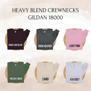 May include: A display of six crewneck sweatshirts in various colors: dark chocolate, dark heather, light pink, military green, sand, and ash grey. The text "HEAVY BLEND CREWNECKS GILDAN 18000" is at the top.
