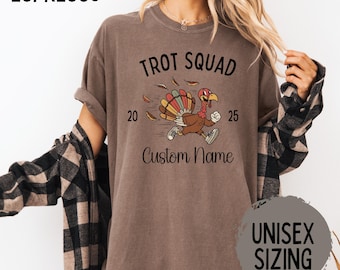 May include: Espresso-colored t-shirt with the text "Trot Squad" and a running turkey graphic. The shirt includes the numbers "20" and "25", and space for a custom name. The shirt is labeled "Unisex Sizing".