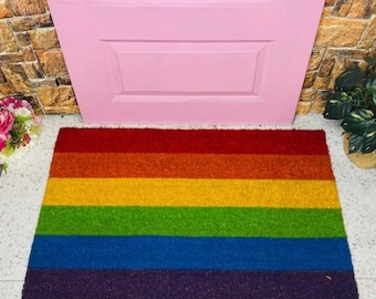 May include: A rainbow doormat with red, orange, yellow, green, blue, and purple stripes. The doormat is made of a soft, textured material and is perfect for adding a pop of color to any entryway.