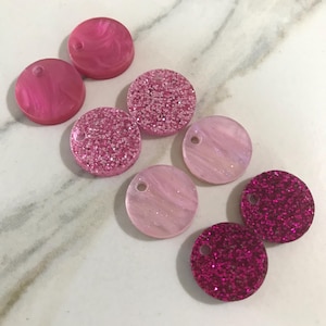 May include: Eight pink and red glitter and swirl patterned round resin embellishments.