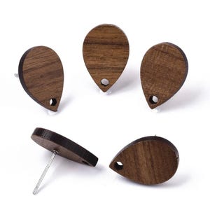 May include: Five wooden teardrop-shaped earrings with a hole in the top. The earrings are a dark brown colour and have a wood grain pattern.
