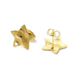 May include: A pair of gold-toned star-shaped stud earrings with a smooth, reflective surface. Each earring features a small circular loop at one of the star points for attaching additional jewellery components and includes a standard post back.