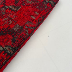 Puede incluir: Un coj&iacute;n rojo y negro con estampado y borde negro. El coj&iacute;n est&aacute; hecho de una tela suave y texturizada.