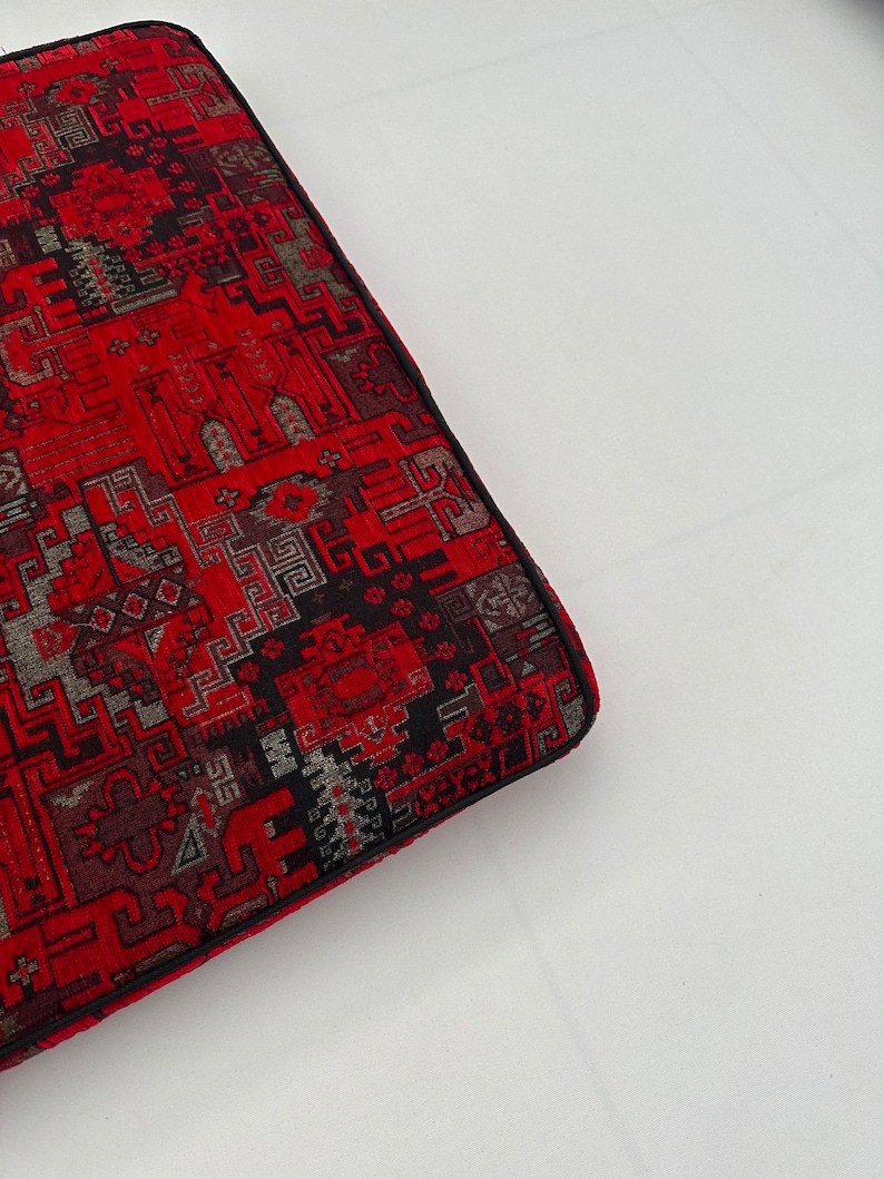 Puede incluir: Coj&iacute;n rojo y negro con estampado y borde negro. El coj&iacute;n est&aacute; hecho de una tela tejida con un dise&ntilde;o geom&eacute;trico.