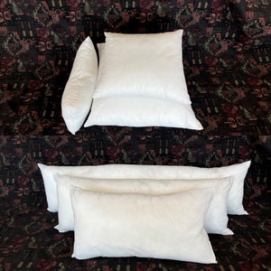 May include: A set of white pillow inserts in various sizes. The pillows are arranged in a stack and a row, showcasing their soft and fluffy texture.