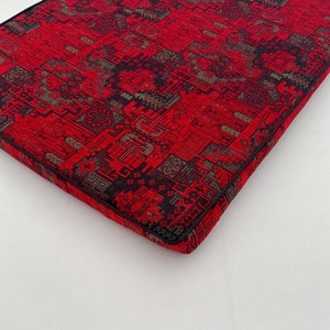 Puede incluir: Coj&iacute;n rojo y negro con estampado y borde negro. El coj&iacute;n tiene un dise&ntilde;o geom&eacute;trico.