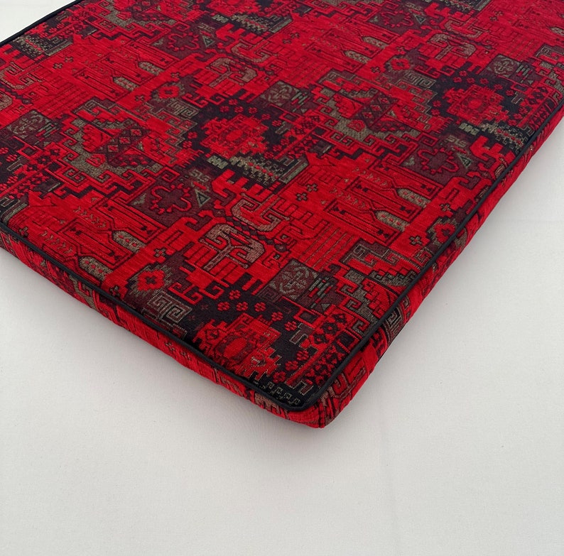 Puede incluir: Coj&iacute;n rojo y negro con estampado y borde negro. El coj&iacute;n tiene un dise&ntilde;o geom&eacute;trico.
