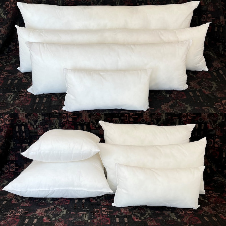May include: A set of white pillow inserts in various sizes, ranging from small to extra-large. The pillows are arranged in a pyramid shape on a patterned fabric background.