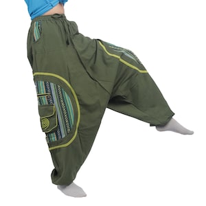 Könnte beinhalten: Grüne, weite Hose mit einem bunten, geometrischen Muster an der Seite. Die Hose hat einen Kordelzugbund und eine weite Beinweite.