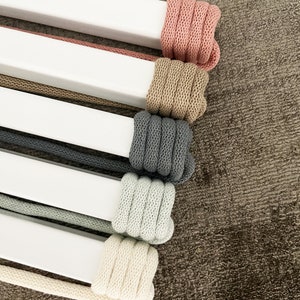 Op de afbeelding: Vijf spoelen met verschillende kleuren katoenen koord gewikkeld rond witte deuvels. De kleuren zijn roze, beige, grijs, lichtgroen en cr&egrave;me.