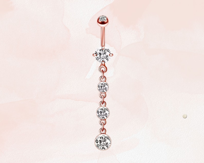 K&ouml;nnte beinhalten: Ein Bauchnabelpiercing aus Ros&eacute;gold mit einer baumelnden Kette aus klaren Zirkonia-Steinen.