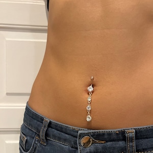 K&ouml;nnte beinhalten: Ein goldener Bauchnabelpiercing mit einer herabh&auml;ngenden Kette aus klaren Strasssteinen.