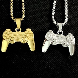 May include: Two gold and silver necklaces with a video game controller pendant. The pendants are detailed with buttons and a directional pad.