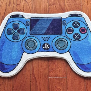 Könnte beinhalten: Ein blauer und weißer Teppich in Form eines Playstation-Controllers. Der Teppich hat einen weißen Rand und blaue Knöpfe.
