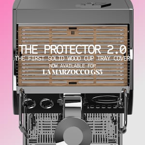 May include: A stainless steel espresso machine with a wooden cup tray cover. The text "THE PROTECTOR 2.0" is displayed, along with "THE FIRST SOLID WOOD CUP TRAY COVER" and "NOW AVAILABLE FOR LA MARZOCCO GS3".