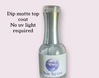 May include: A clear bottle of MoonDust Nail Dips Matte Top Coat. The bottle has a silver cap and a white label with the company logo and the words "Matte Top Coat".